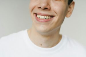 A close-up shot of a young man smiling, highlighting his teeth and expression.